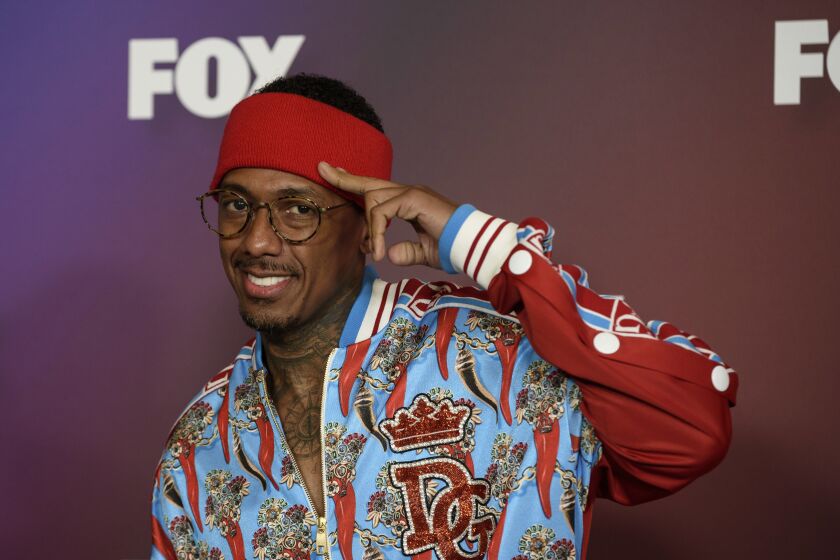 A man wearing glasses, a brightly colored jacket and a headband salutes the camera