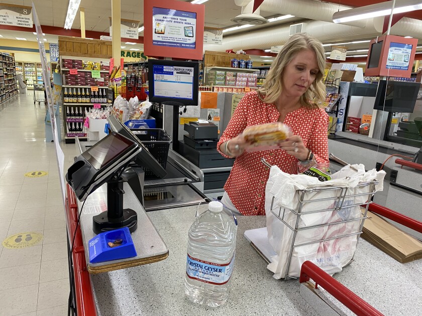 A woman bagging groceries at a largely empty supermarket 