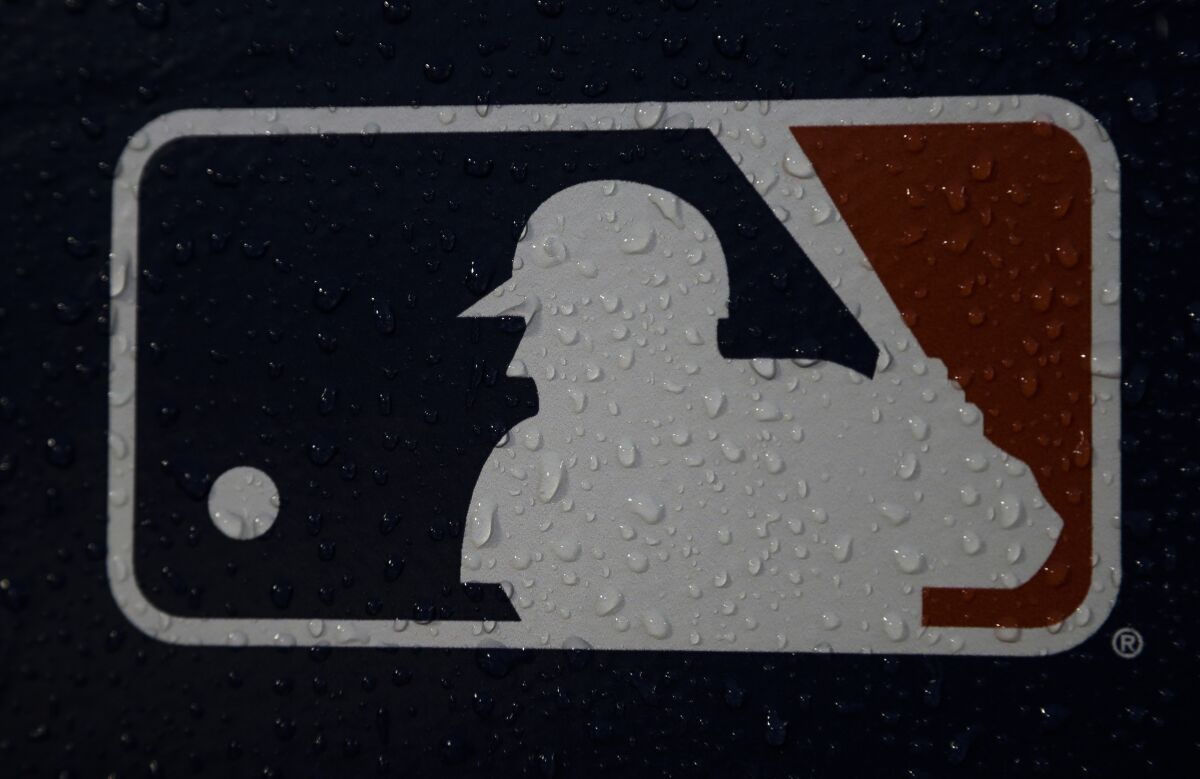 FILE - A rain-covered logo is seen at Fenway Park before Game 1 of the World Series baseball game between the Boston Red Sox and the Los Angeles Dodgers Tuesday, Oct. 23, 2018, in Boston. The mood for Major League Baseball fans is a little glum these days as the players' union and owners continue to bicker over finances. The owners locked out the players on Dec. 2 and unless an agreement between the two sides is reached soon, the spring training schedule is in trouble. The first games are slated for Feb. 26, 2022. (AP Photo/Matt Slocum, File)