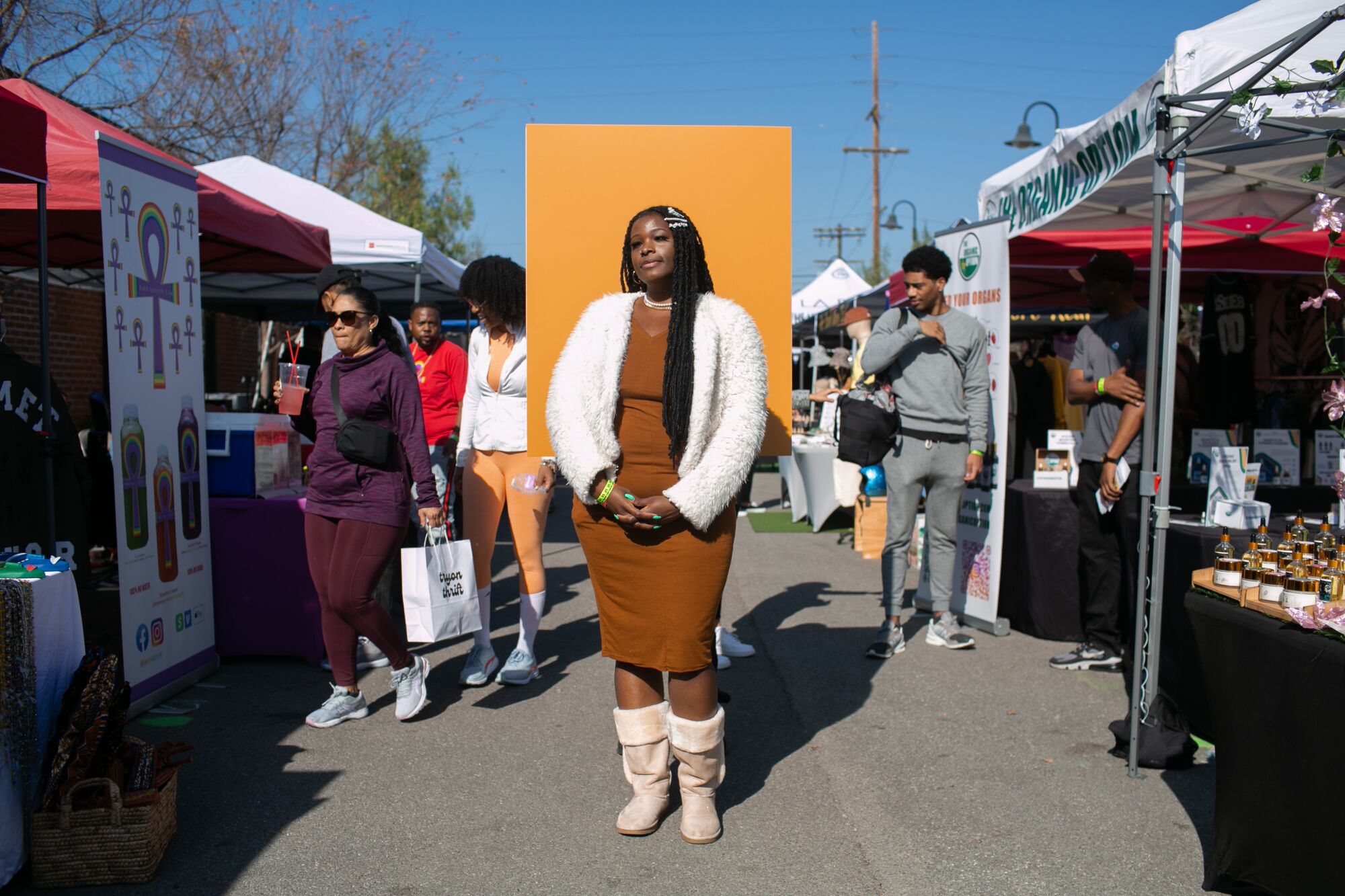 A woman in a brown dress with white boots and jacket at an outdoor market