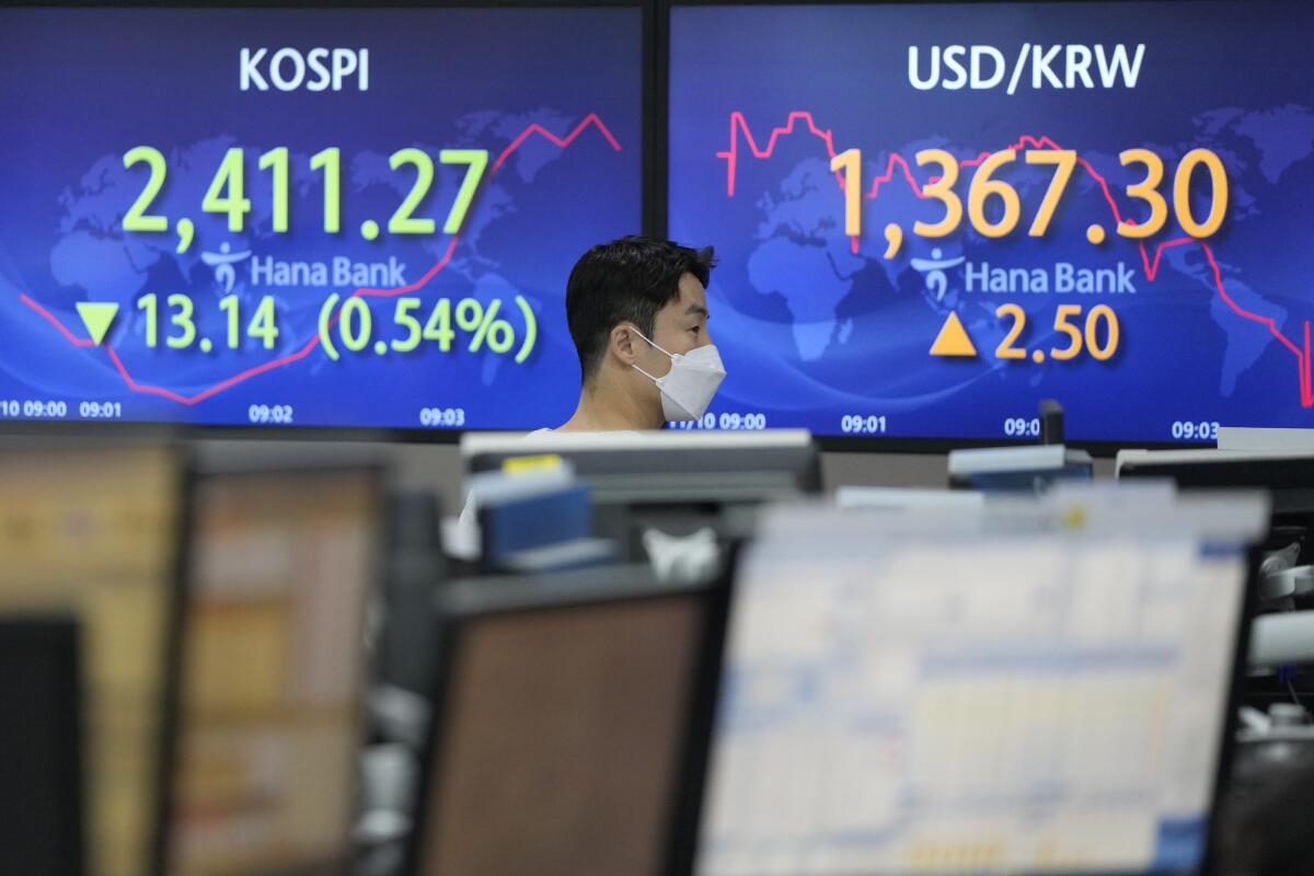 A currency trader walks by screens showing the Korea Composite Stock Price Index (KOSPI), left, and the exchange rate of South Korean won against the U.S. dollar, at the foreign exchange dealing room of the KEB Hana Bank headquarters in Seoul, South Korea, Thursday, Nov. 10, 2022. Asian stock markets followed Wall Street lower on Thursday ahead of a U.S. inflation update that will likely influence Federal Reserve plans for more interest rate hikes after elections left control of Congress uncertain.(AP Photo/Ahn Young-joon)