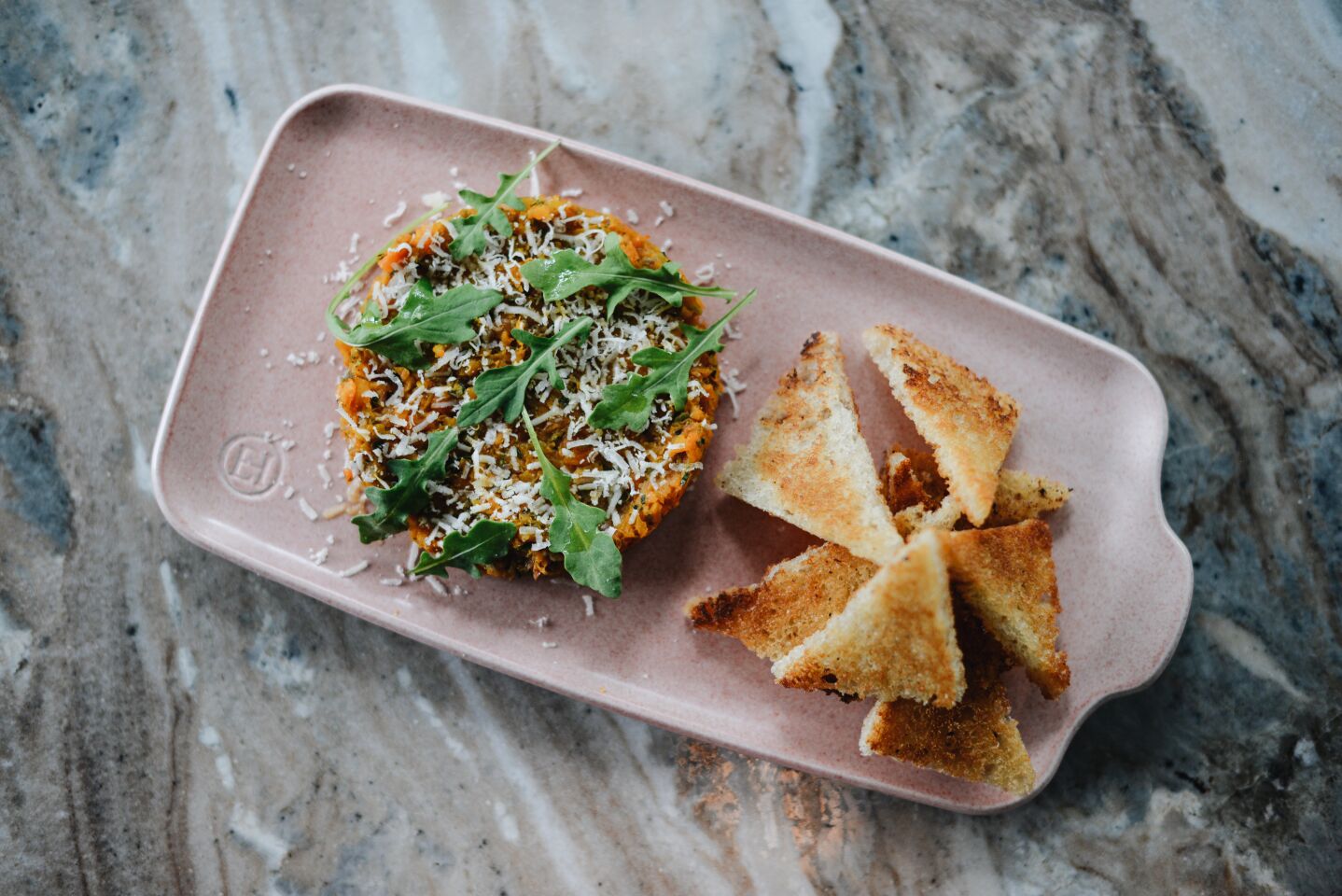 The carrot tartare is garnished with pecorino, arugula and Texas toast points.