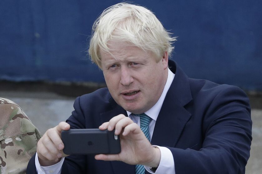 FILE - British Foreign Secretary Boris Johnson, right, takes a photo of a Nigeria Naval worship with his phone camera, during a visit to the Nigeria Navy at the Naval dockyard in Lagos, Nigeria Thursday, Aug. 31, 2017. The British government is facing a Thursday deadline to hand over a sheaf of former Prime Minister Boris Johnson’s personal messages to the country’s COVID-19 pandemic inquiry. (AP Photo/ Sunday Alamba, File)