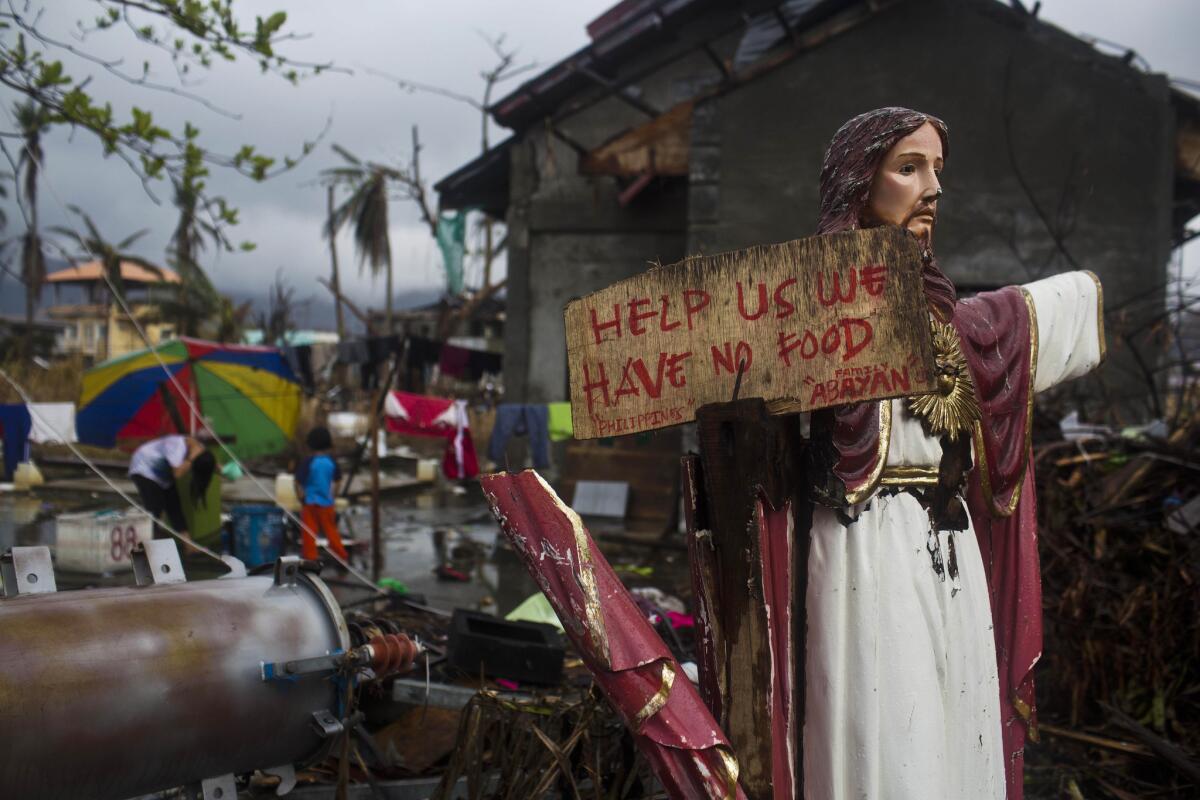 A plea for help painted on a sign hangs from a damaged statue of Jesus in Tacloban, Philippines. Officials disclosed Friday that the death toll has climbed to 5,209 and ordered a speed-up of rebuilding to house the 4 million left homeless by the Nov. 8 storm.