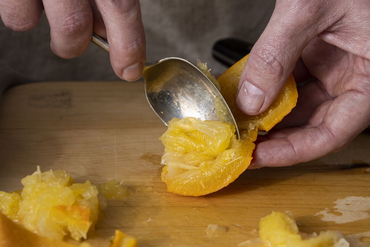LOS ANGELES, CALIFORNIA, Jan. 19, 2022: Step-by-step citrus marmalade-cooking guide: scraping cooked Seville oranges 