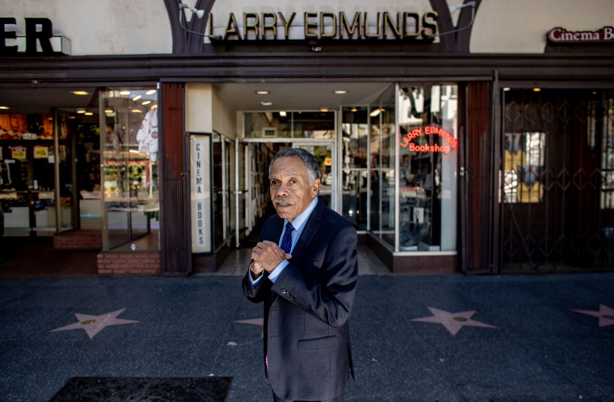 Un hombre con traje y corbata se para frente a una librería.