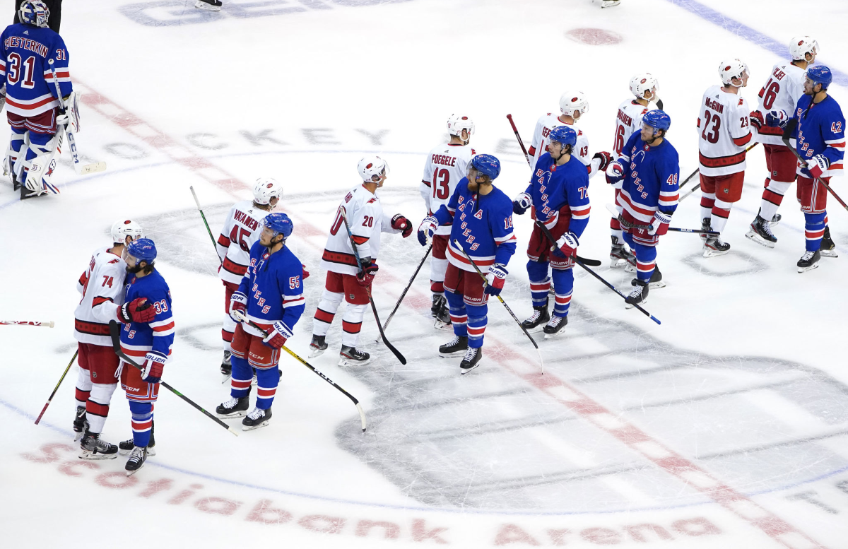 Members of the Carolina Hurricanes and New York Rangers bump gloves at the conclusion of a playoff qualifying series.
