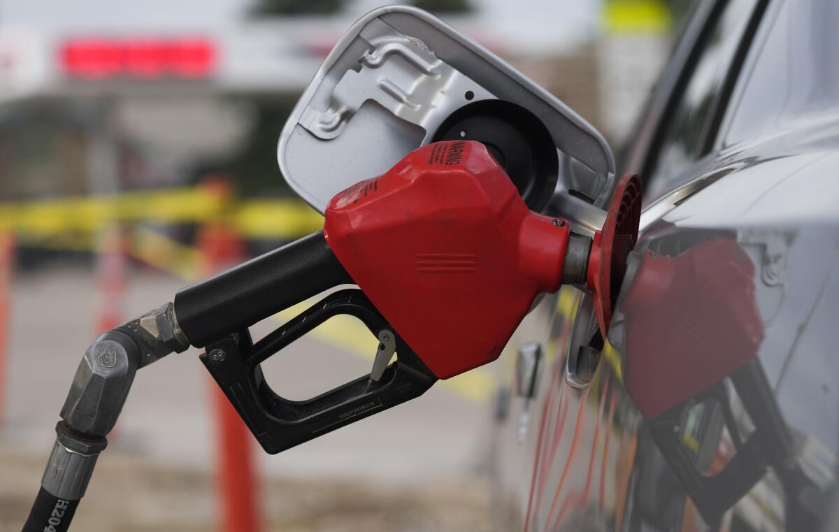 The handle of a fuel pump rests inserted into a vehicle's gas tank. 