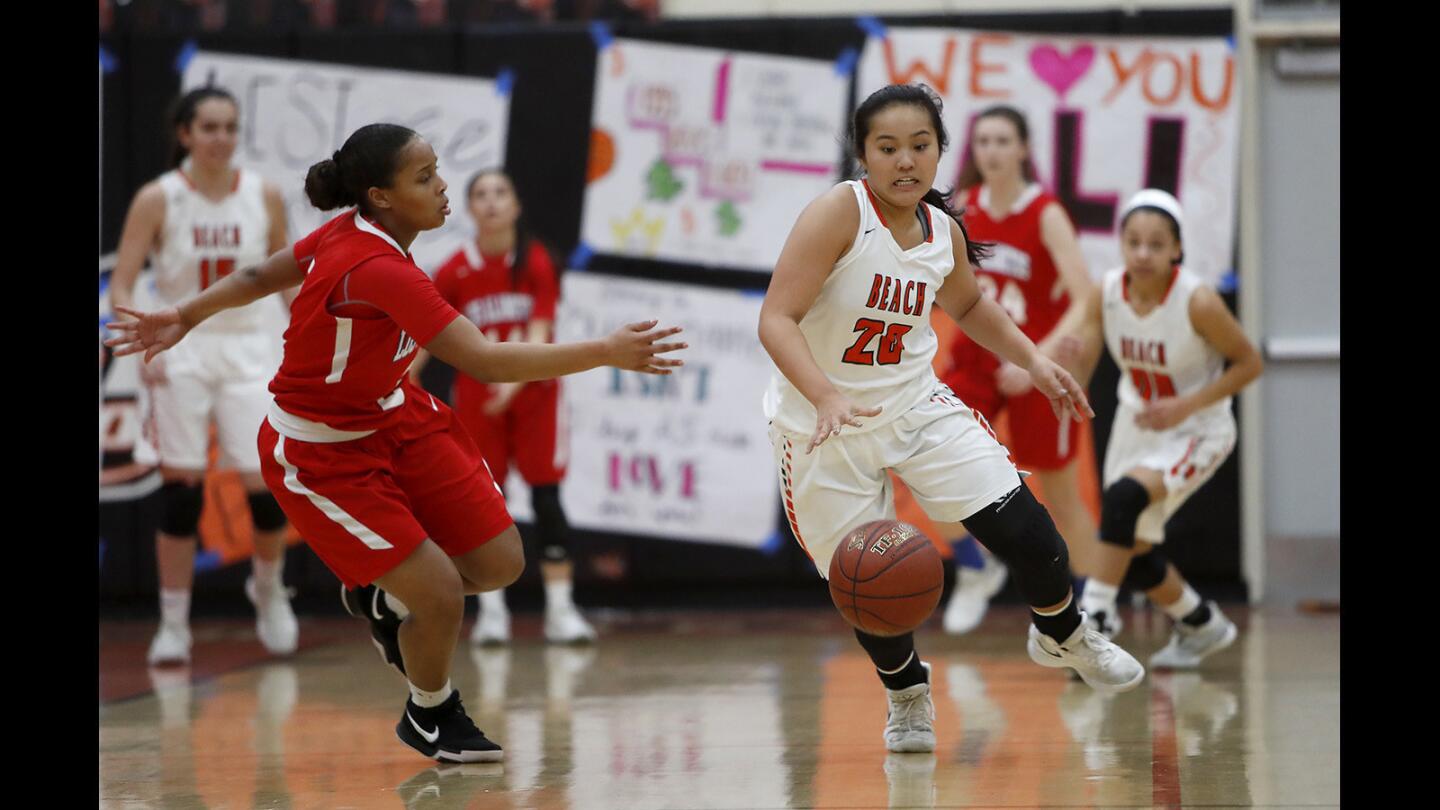 Huntington Beach High's Marisa Tanga, right, steals the ball from Los Alamitos' Asia Avinger, left, before scoring a layup during the first half in a Sunset League game on Monday in Huntington Beach.