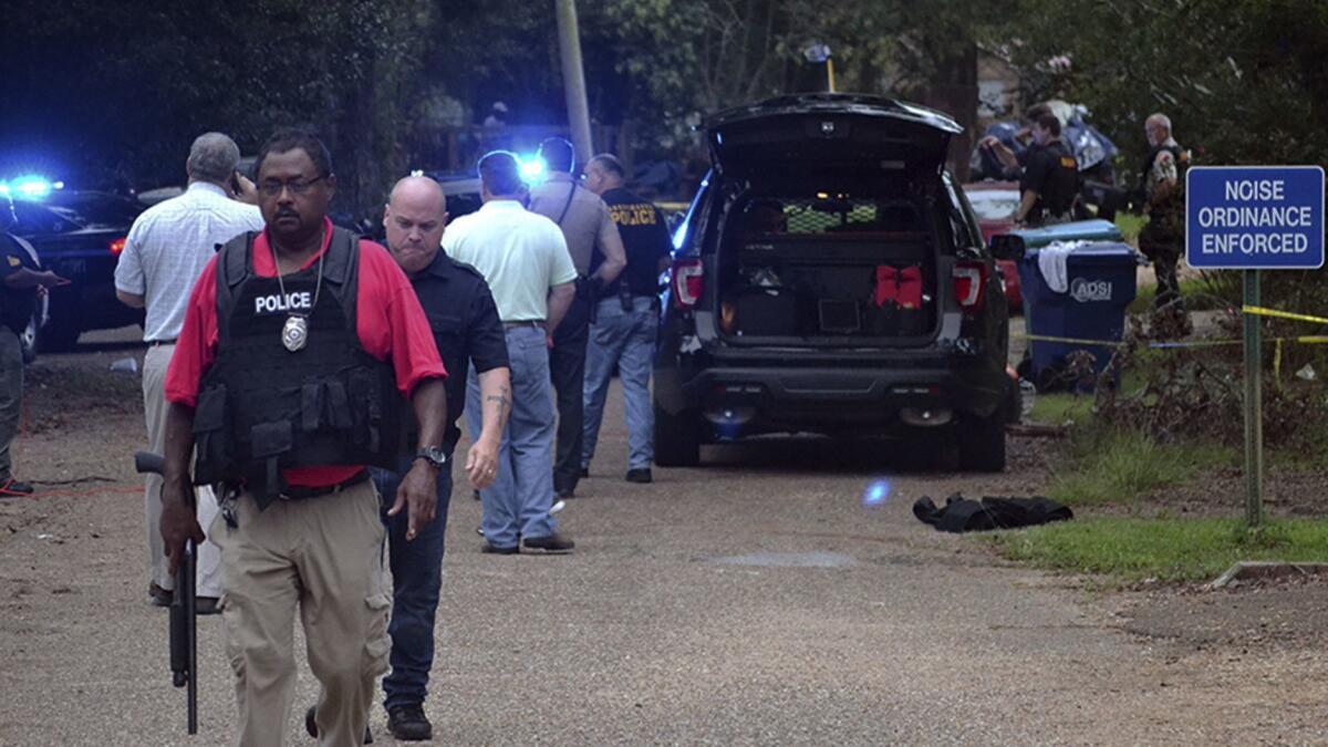 Law enforcement agents secure the scene of a shooting in Brookhaven, Miss., where two police officers were killed Saturday morning. A suspect was wounded and taken into custody.