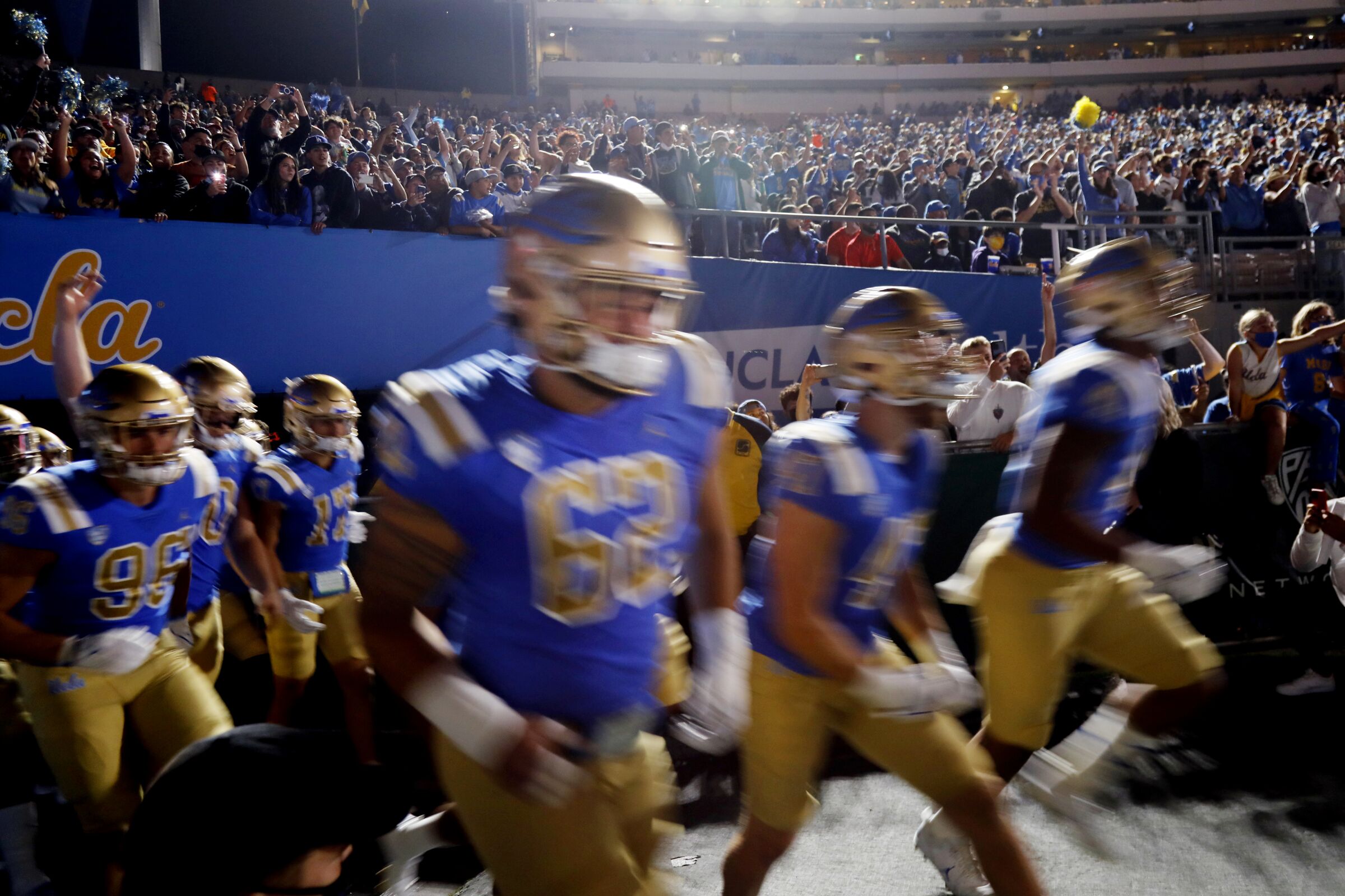 UCLA players rush onto the football field.