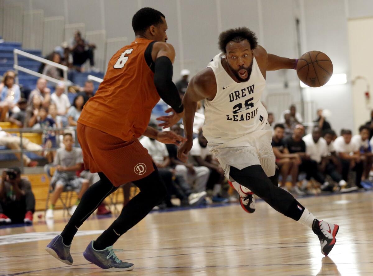 Mike Efevberha, left, tries to guard former Clippers and Warriors star Baron Davis during a Drew League game in the Southwest College gym on Aug. 12