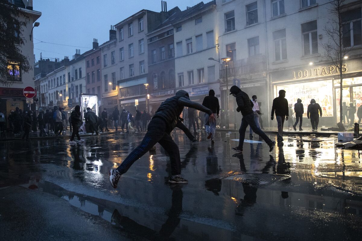 Protestors thrown stones in the Belgium capital, Brussels, Wednesday, Jan. 13, 2021, at the end of a protest asking for authorities to shed light on the circumstances surrounding the death of a 23-year-old Black man who was detained by police last week in Brussels. The demonstration in downtown Brussels was largely peaceful but was marred by incidents sparked by rioters who threw projectiles at police forces and set fires before it was dispersed. (AP Photo/Francisco Seco)