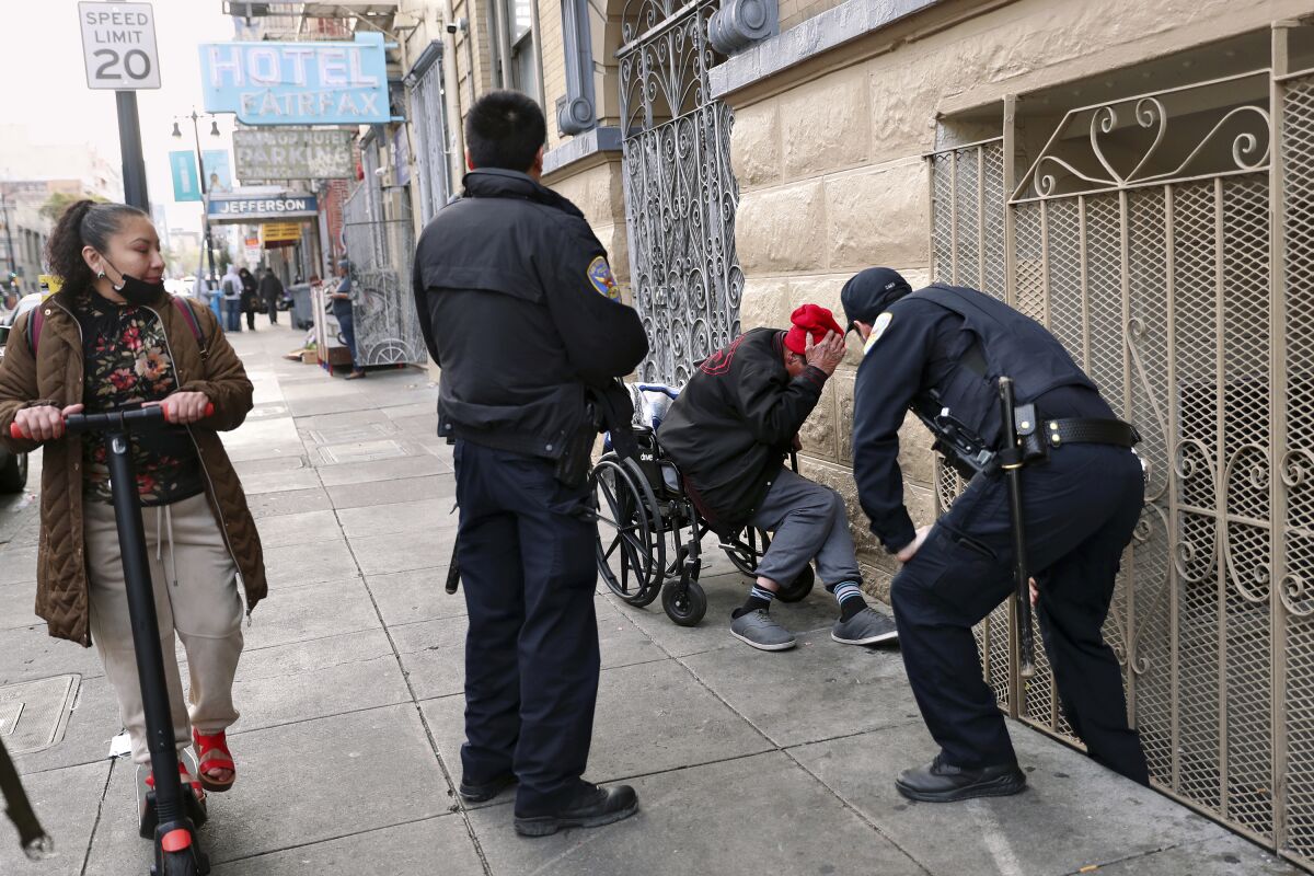 FILE - San Francisco police officers wake up a sleeping homeless man and ask him to move along Eddy Street near the Jefferson Hotel in San Francisco, on March 15, 2022. A one-night count found San Francisco's homeless population dipped slightly to roughly 7,800 people in 2022. The last point-in-time count found more than 8,000 residents in 2019 in a city where unhoused people are highly visible. (Scott Strazzante/San Francisco Chronicle via AP, File)/San Francisco Chronicle via AP)