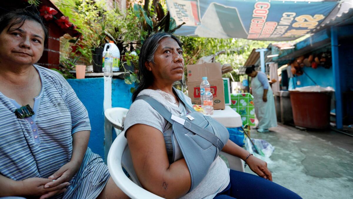 Leodegaria Comonfor Ramirez, 49, center, whose home collapsed in the recent quake, killing her daughter, has a fractured shoulder and now shares a home with her neighbors.