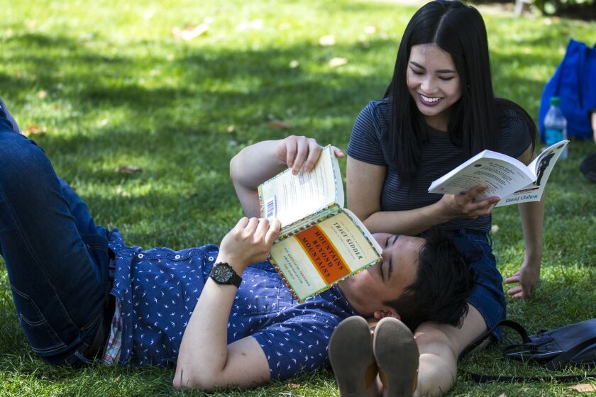 Jason Ham, 23, of Los Angeles rests his head on Baily Pham's legs while they read books during the Los Angeles Times Festival of Books at USC on Sunday.