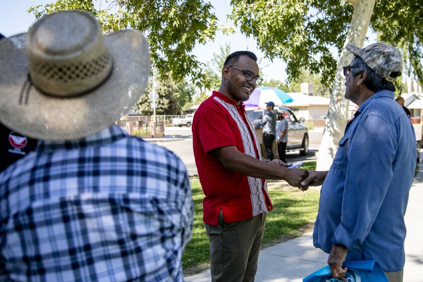 WASCO, CA - JUNE 24, 2021: Mayor Alex Garcia, middle, shakes a residents hand while giving out $25 gifs cards to farm workers during a gift card-/food box distribution behind a community center on June 24, 2021 in Wasco, CA. Garcia is the only LGBT politician in the Central Valley. Recently, he tried to get the city to fly the Pride flag, but was outvoted 4-1.(Gina Ferazzi / Los Angeles Times)