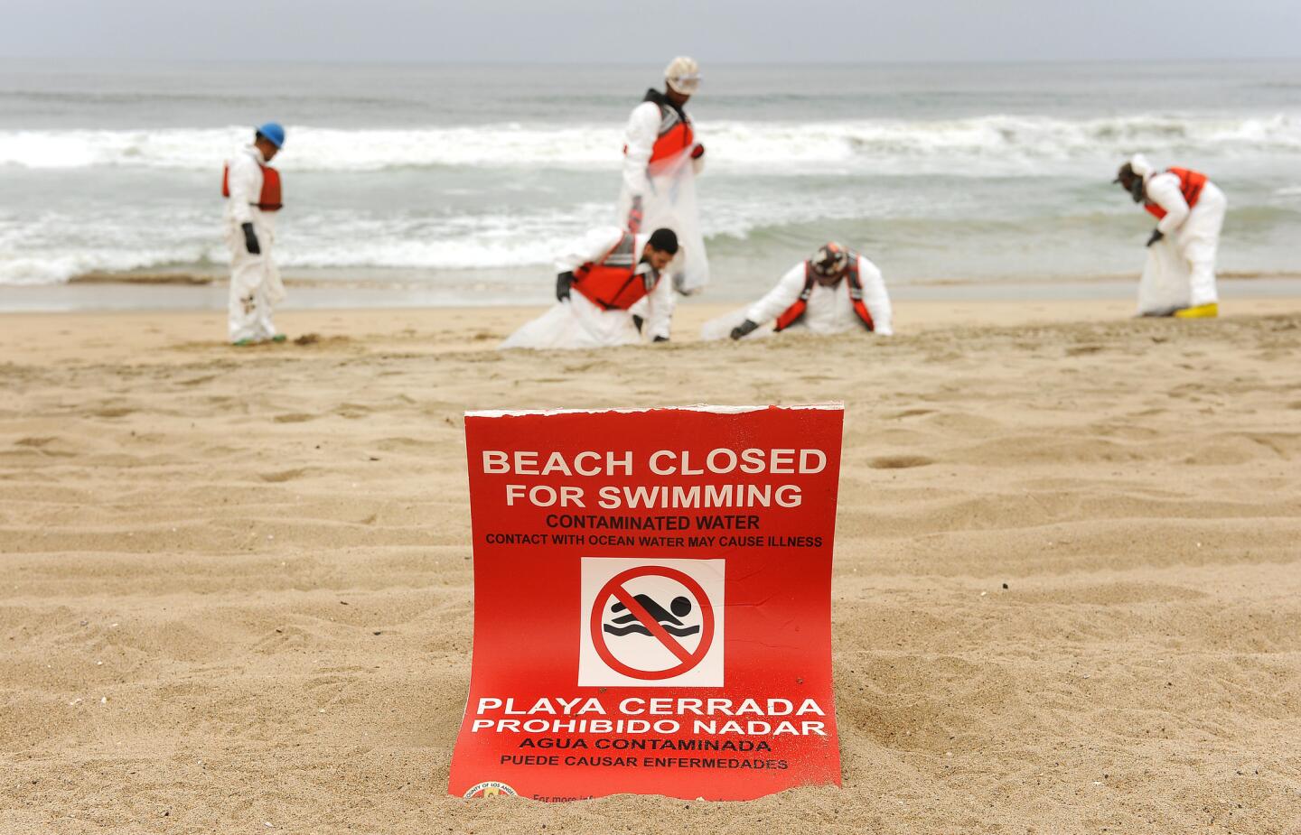 Posted signs warn people not to make contact with ocean water in Manhattan Beach on May 28 as workers clean up a tar-like substance along the South Bay shoreline.