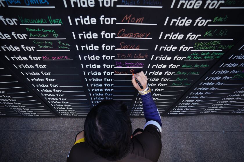 Cyclisst add names of family and friends to a wall to declare who they ride for at "Padres Pedal the Cause." The event raises money for local cancer research.