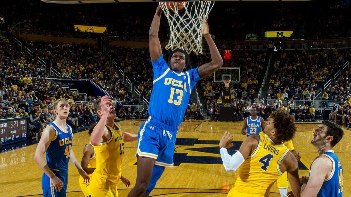 UCLA guard Kris Wilkes dunks the ball, going up between Michigan forward Moritz Wagner (13) and forward Isaiah Livers (4), in the second half on Saturday in Ann Arbor, Mich.