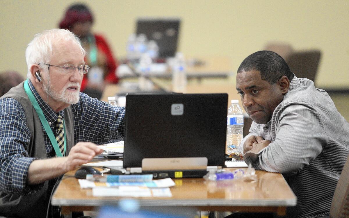 Mike Everding, left, helps James Randle sign up for a Covered California plan at an enrollment event in March in Inglewood.