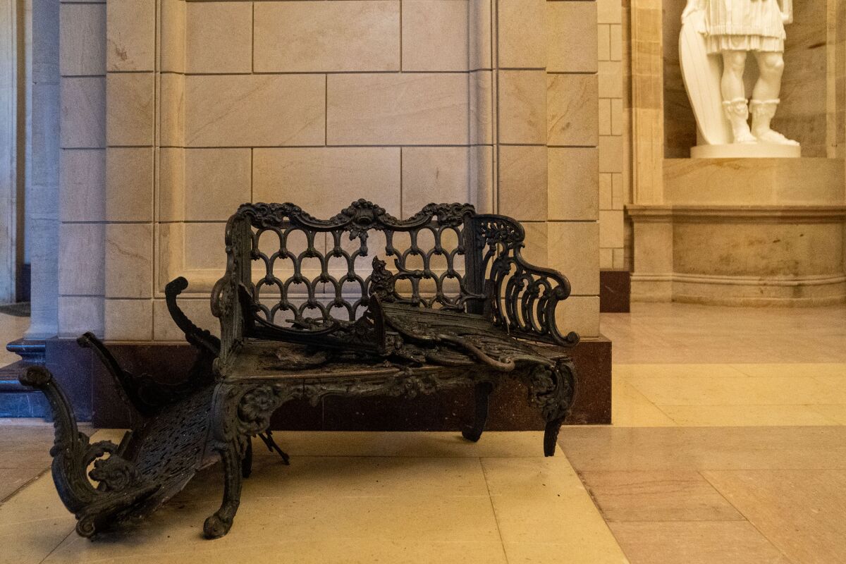 An ornate wrought-iron bench is shown in pieces inside the Capitol building.