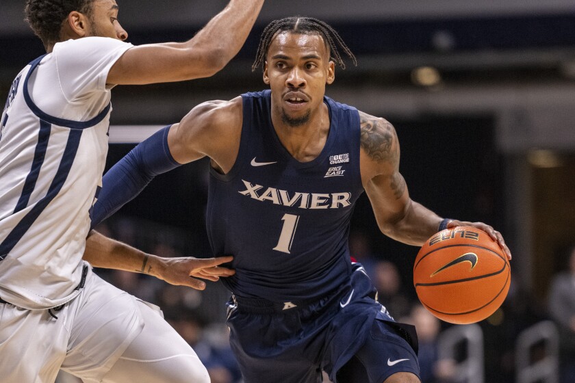 Xavier guard Paul Scruggs (1) drives against Butler guard Aaron Thompson during the first half of an NCAA college basketball game against Butler, Friday, Jan. 7, 2022, in Indianapolis. (AP Photo/Doug McSchooler)