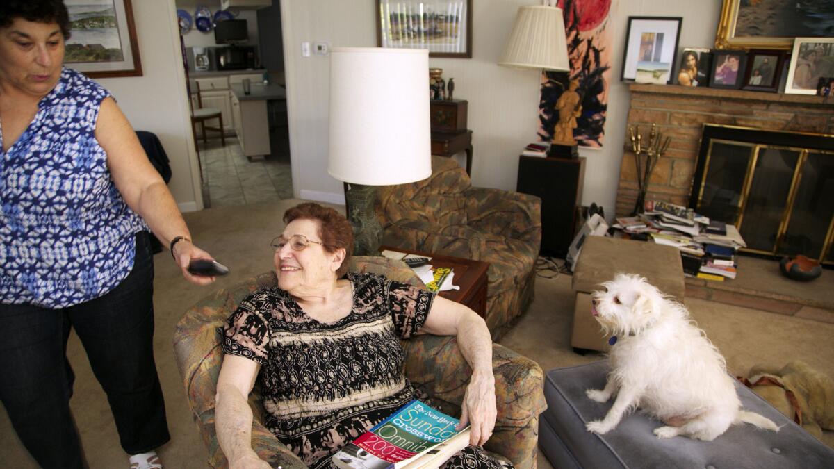 Eleanor Blum, 88, sits with with her dog "Cutie" as her daughter, Jeri Vargas, brings her a wireless phone in Sherman Oaks.