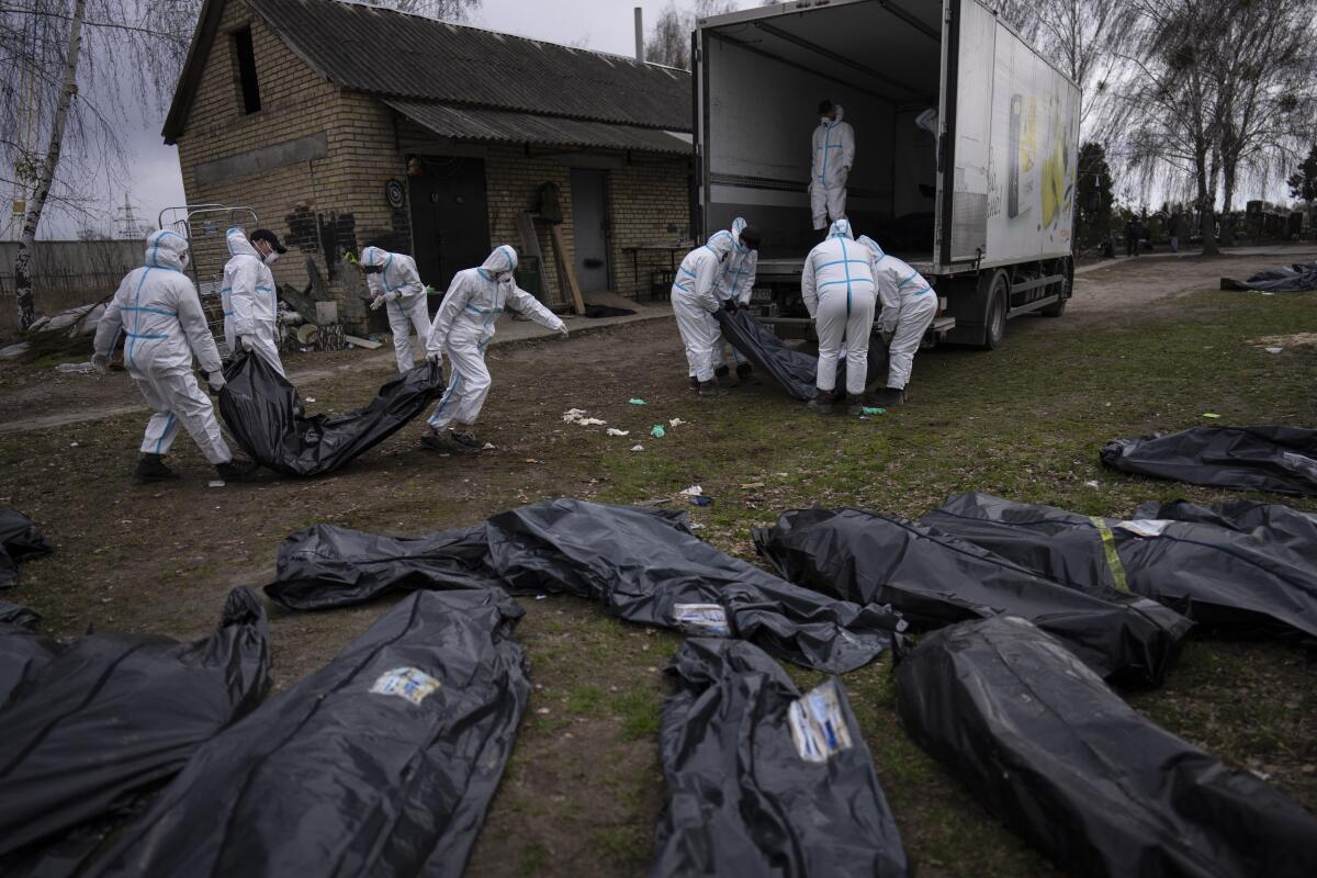 FILE - Volunteers load bodies of civilians killed in Bucha onto a truck to be taken to a morgue for investigation, in the outskirts of Kyiv, Ukraine, Tuesday, April 12, 2022. Ministers from dozens of nations are meeting on Thursday, July 14, 2022 in the Netherlands to discuss with the International Criminal Court’s chief prosecutor how best to coordinate efforts to bring to justice perpetrators of war crimes in Ukraine. (AP Photo/Rodrigo Abd, File)