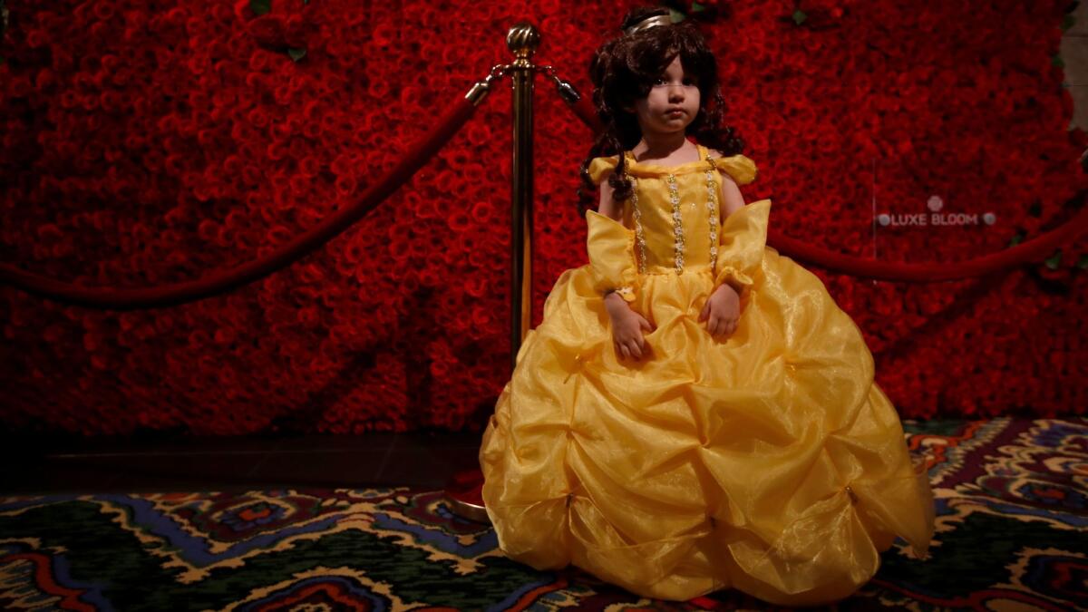 Olivia Bustillos, 3, of El Monte poses in front of a wall of roses in the lobby of Hollywood's El Capitan Theatre during the first public screening of "Beauty and the Beast" on March 16.