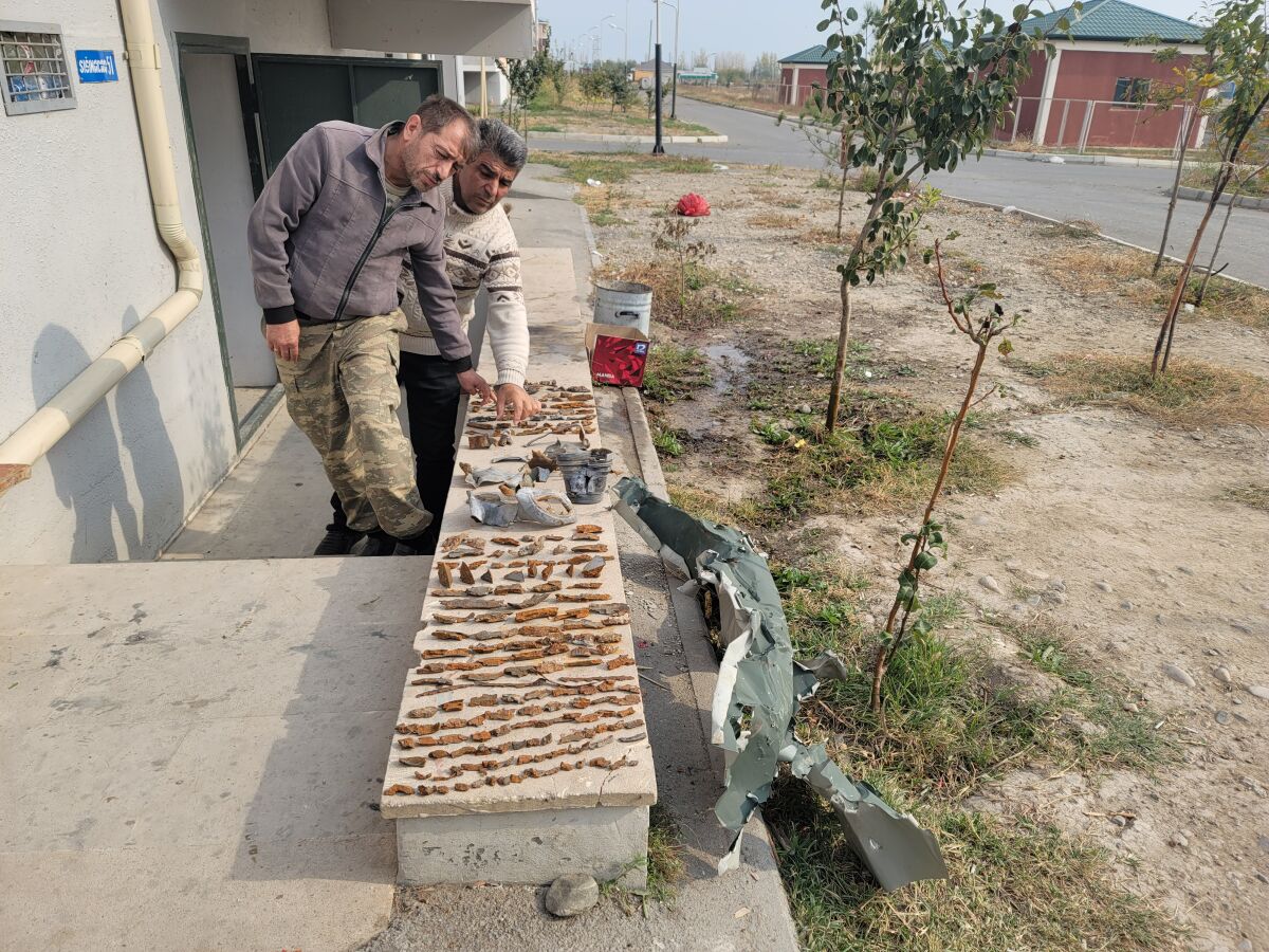 Wafadar Aliyev and Aydin Shahverdiyev collect shrapnel from a barrage on their settlement in Azerbaijan