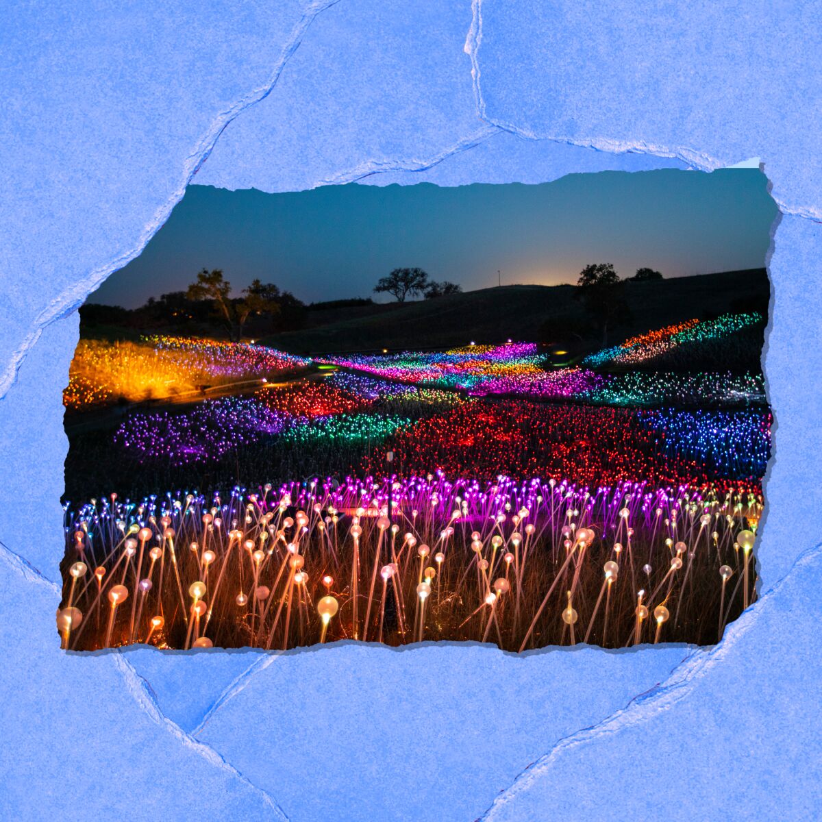 At dusk, rolling hills are covered with patches of tiny lights in varying colors.