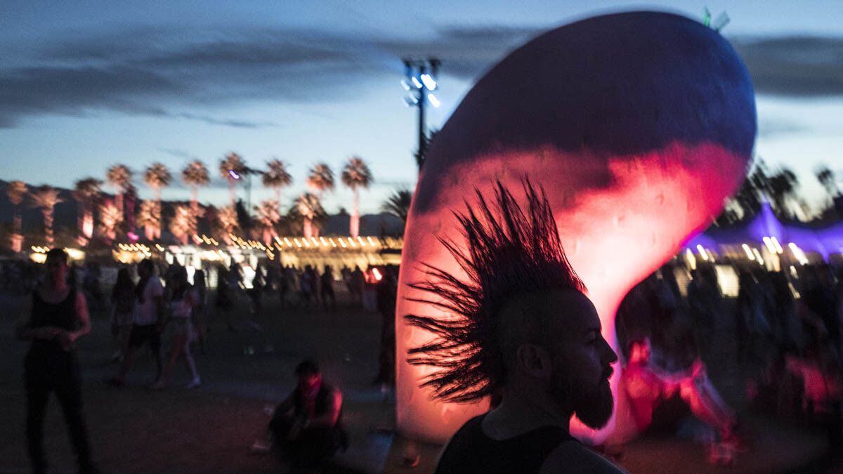 INDIO, CALIF. -- SUNDAY, APRIL 16, 2017: A festival goer with a spiked mohawk passes through the 'Chiaozza Garden' art installation at the Coachella Music and Arts Festival in Indio, Calif., on April 16, 2017. (Brian van der Brug / Los Angeles Times)
