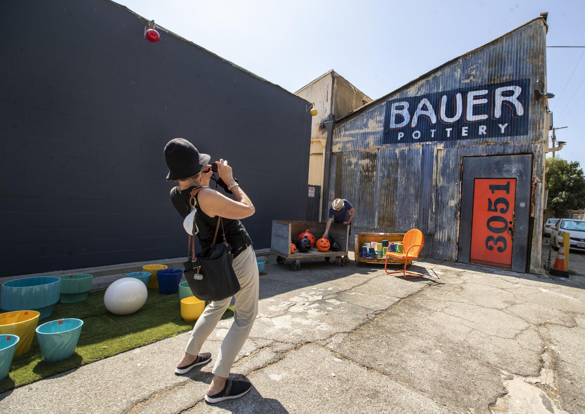 A woman takes a photo of the industrial exterior of the Bauer Pottery showroom