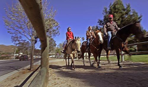 Lori Hall, her daughter Ali and friend Edward "Buzz" Riebschlager ride along the dirt trails off Sixth Street in Norco. Most of Norco's neighborhoods are connected by horse trails.