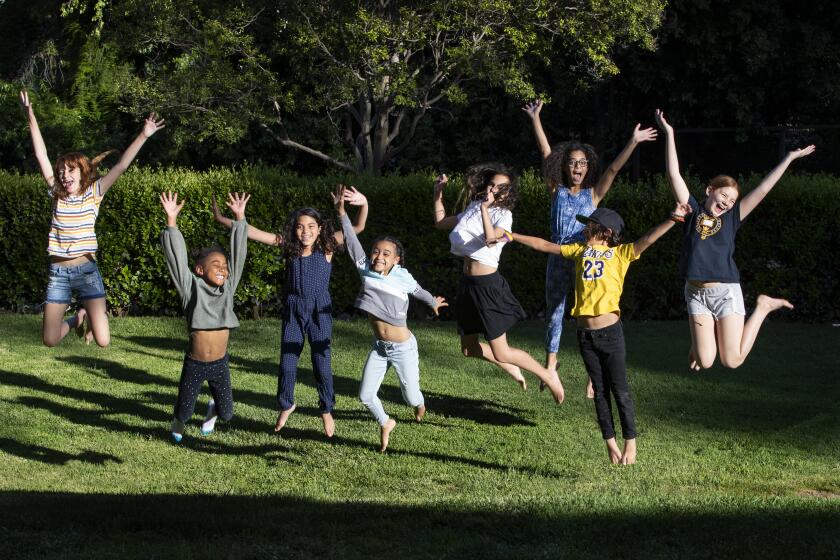 RIVERSIDE, CA- MAY 5, 2020: The students of "Brothbush Academy" cheer for their home school on the Roth's front lawn in the midst of the coronavirus pandemic on May 5, 2020 in Riverside, California. From the left; Kat Bristow, Andie Bristow, Rosie Roth, Allison Furbush, Penelope Roth, Sylvester Roth, Carmen Furbush, and Ellie Bristow. The Bristow's, Roth's and Furbush's, who are also neighbors, have quarantined together and are home schooling the 8 children amongst them using the parents as teachers. They've named the school "Brothbush Academy" coined from the families' last names.(Gina Ferazzi / Los Angeles Times)