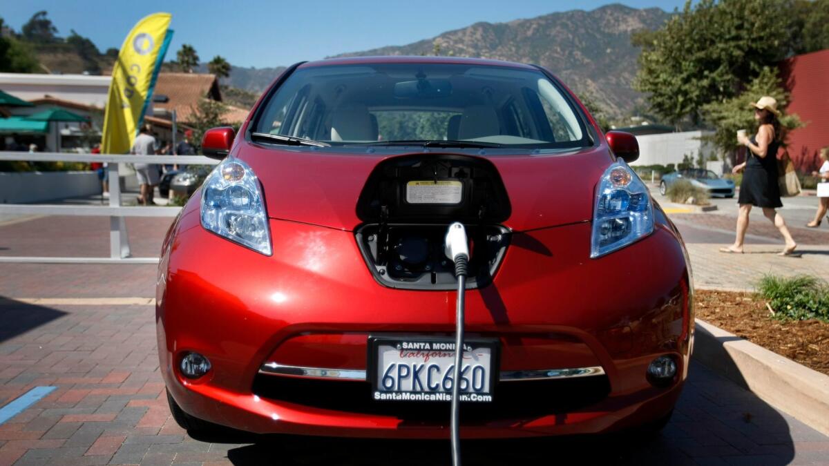 A Nissan Leaf is plugged into an electric-vehicle charging station at the Malibu Country Mart.