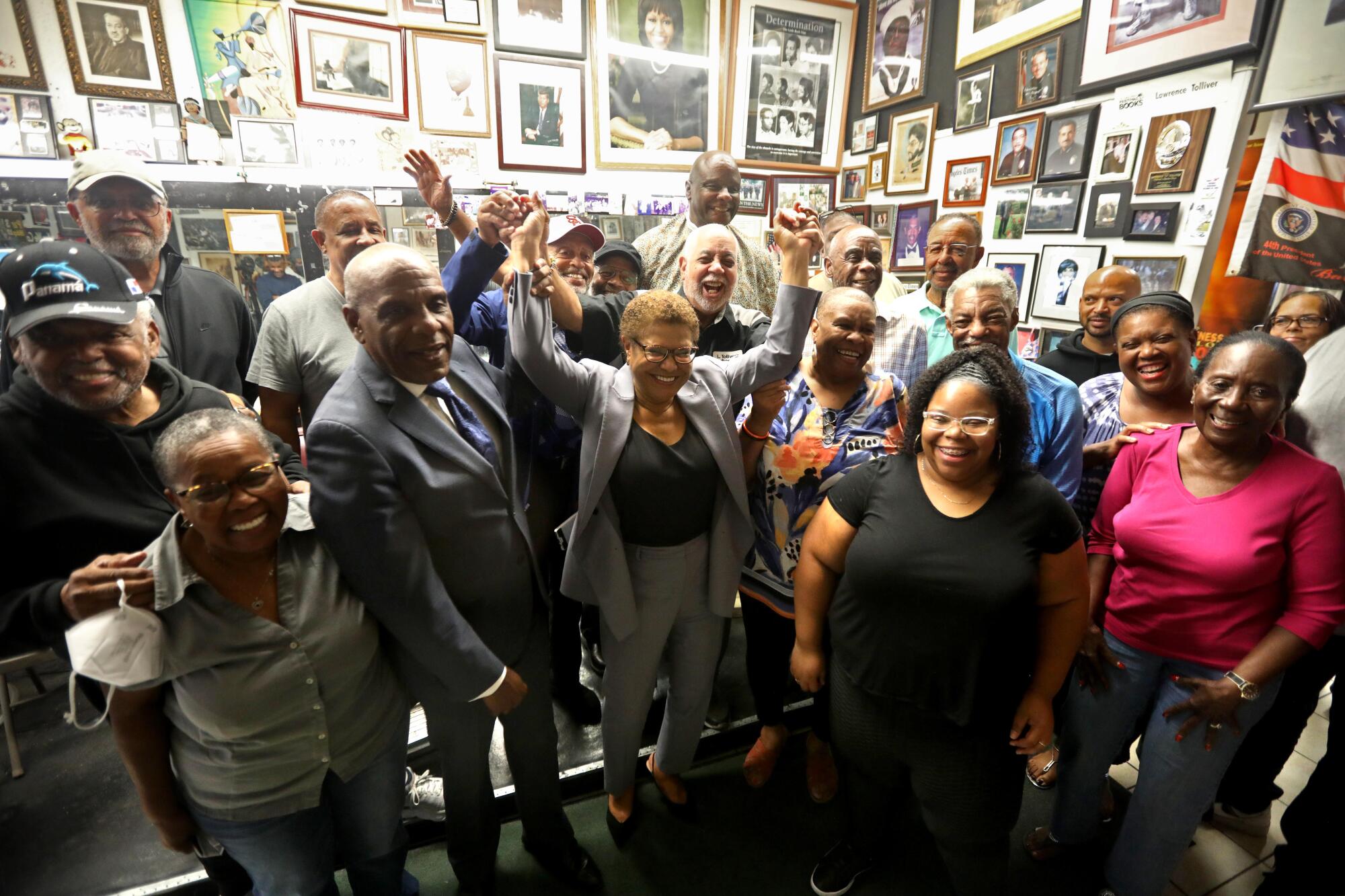 Lawrence Tolliver, center, holds Rep Karen Bass's arms up, as others show their support for Bass running for mayor 