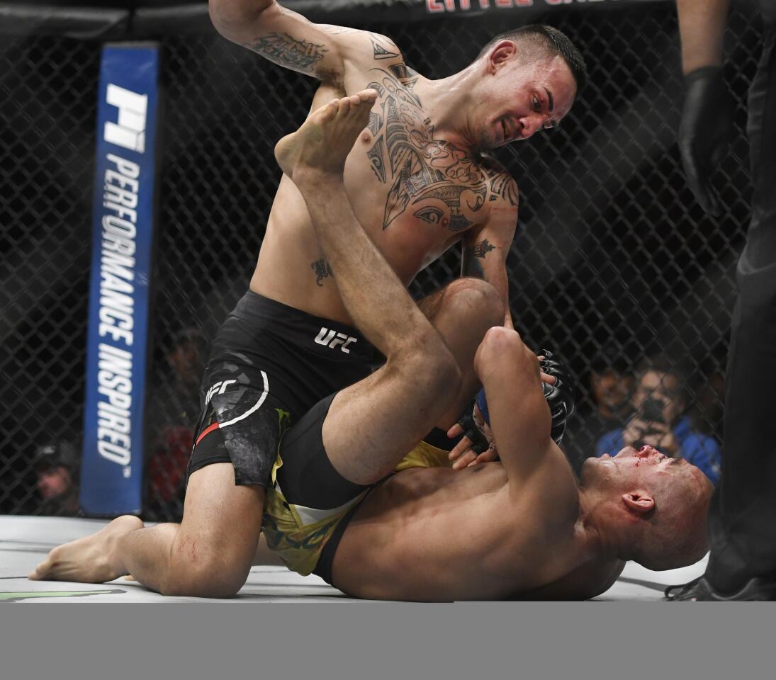 Max Holloway, top, punches Jose Aldo, of Brazil, during the third round of a UFC 218 featherweight mixed martial arts bout, early Sunday, Dec. 3, 2017, in Detroit. Holloway won the bout. (AP Photo/Jose Juarez)