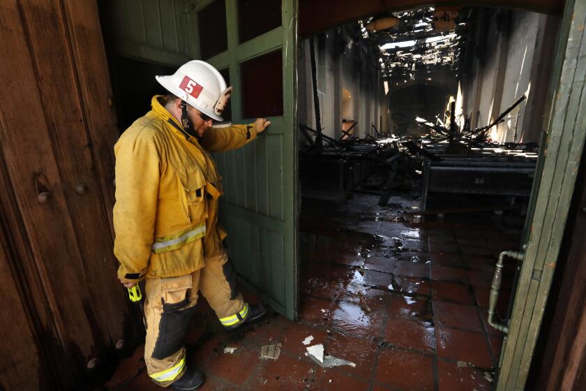 SAN GABRIEL, CALIFORNIA-JULY 11, 2020-San Gabriel Fire Captain David Mulligan closs the doors to the San Gabriel Mission that was severly damaged in an overnight fire on July 11, 2020. The 249-year-old San Gabriel Mission caught fire overnight and burned most of the roof and interior. The cause is unknot at this time.(Carolyn Cole/Los Angeles Times)