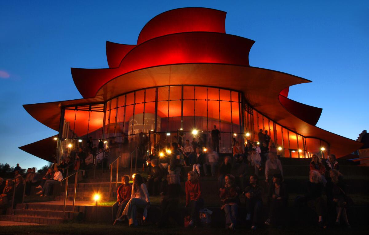 FILE - In this Sept.22, 2006 file photo people sit in front of the illuminated Potsdam's new Hans Otto theater after the opening ceremony. The new building was designed by Pritzker Architecture price awarded German architect Gottfried Boehm. Boehm died Wednesday, aged 101. (AP Photo/Sven Kaestner, file)