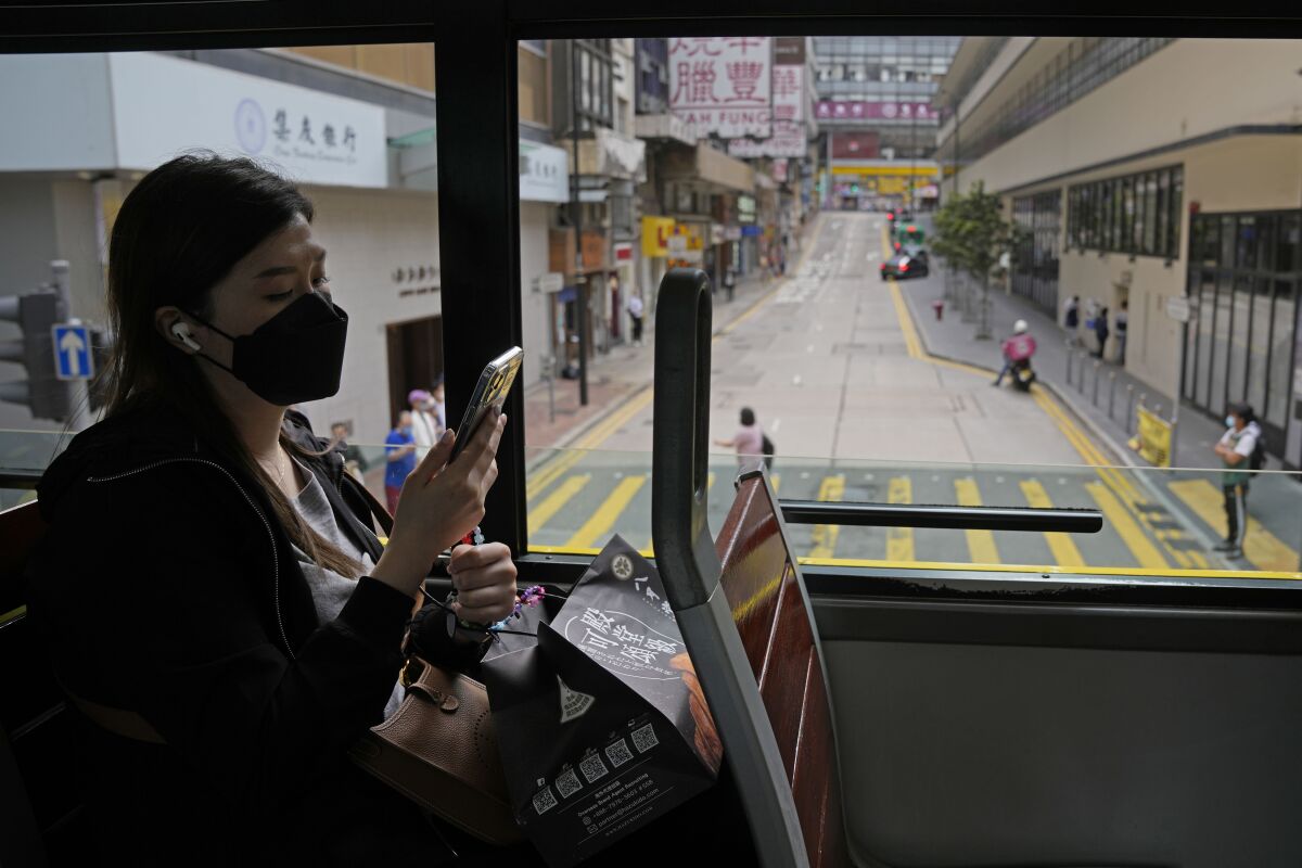A woman wearing a face mask rides on a tram in Hong Kong, Wednesday, March 16, 2022. (AP Photo/Kin Cheung)
