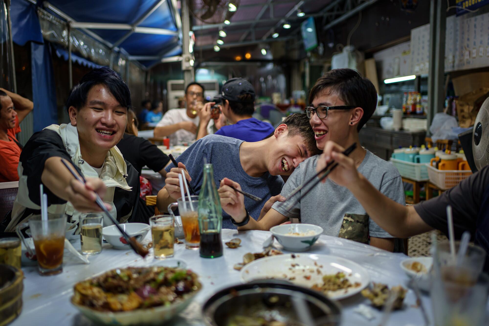 Members of the band Boyz Reborn Kevin Shek, left, Tommy So and Sam Lee share a light moment together during dinner.