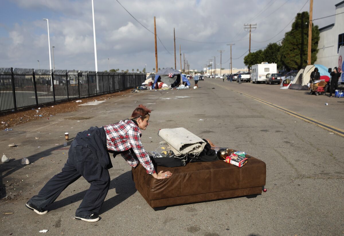 Alexis Russ moves some of her belongings as workers clean up a homeless encampment on Feb. 1.