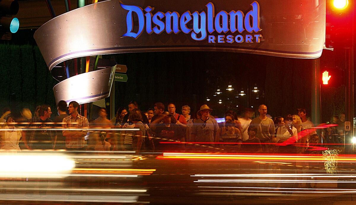 Disneyland visitors wait to cross Harbor Boulevard on its eastern side. The theme park has lived up to Walt Disney's aim to create a fantasyland hidden away from the metropolis around it, though its architecture has seeped out onto the boulevard to beckon tourists and residents alike.