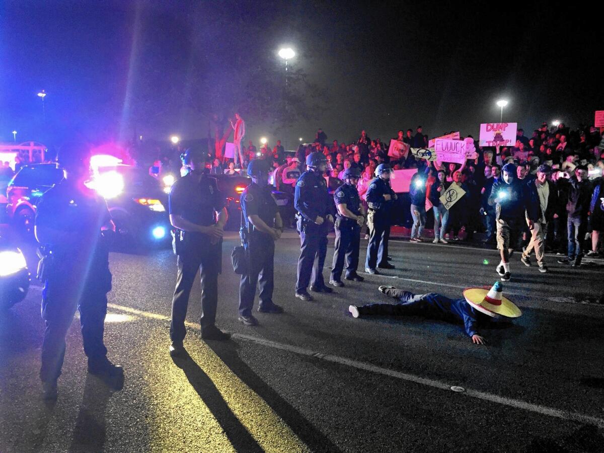 A demonstrator against Donald Trump lies before a line of Costa Mesa police officers at the intersection of Fair Drive and Fairview Road near the Pacific Amphitheater, where the candidate’s freewheeling speech was cheered by more than 8,000 supporters.