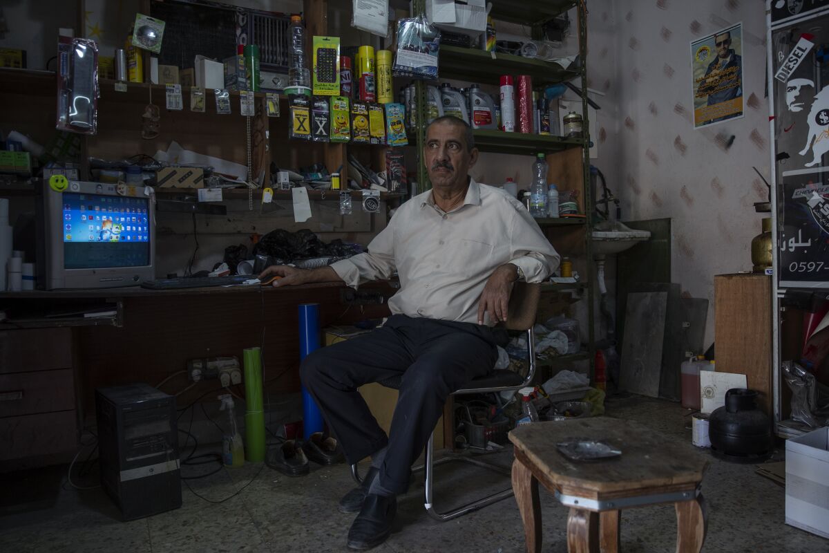 Palestinian Mustafa Erekat, whose son Ahmed was shot dead by Israeli forces at a West Bank checkpoint last year and held his body after, sits at his shop in the village of Abu Dis, South of Ramallah, Tuesday, Sept. 21, 2021. (AP Photo/Nasser Nasser)