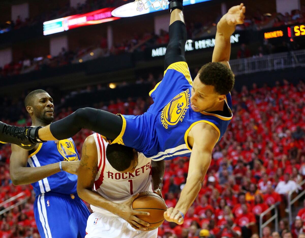 Warriors guard Stephen Curry falls over Rockets forward Trevor Ariza in the second quarter. Curry left the game after hitting his head on this fall, but returned in the second half.