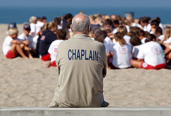 Huntington Beach Police Department Chaplain Roger Wing watches from a distance as small groups of Junior Lifeguards gather to talk about the death of Allyssa Squirrell, 11. Squirrell died after being hit by the propeller of a lifeguard boat during exercises on Wednesday.