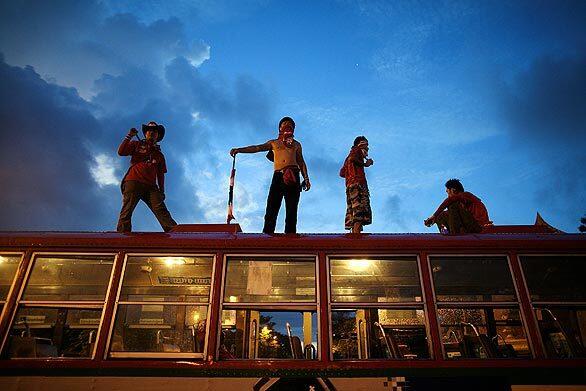 Supporters of former Thailand Prime Minister Thaksin Shinawatra stand on a bus early Monday morning outside Government House in Bangkok. Prime Minister Abhisit Vejjajiva on Sunday declared a state of emergency in Bangkok and five neighboring provinces, one day after anti-government protesters cancelled a 16-nation regional summit.